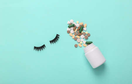 False eyelashes with bottle of pills on blue background. top viewの写真素材