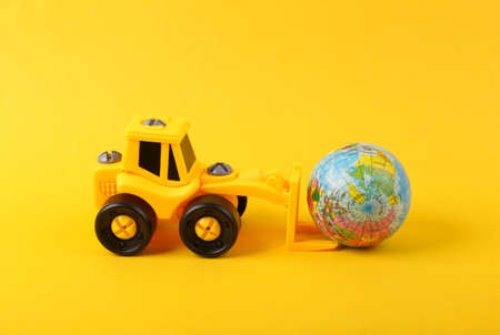 Toy forklift with globe on yellow backgroundの写真素材