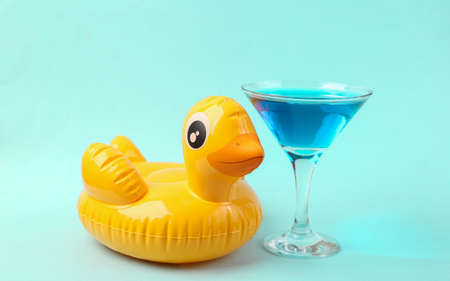 Inflatable yellow duck with cocktail on a blue background. pool party. summer fun concept