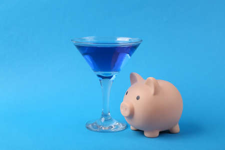 Margarita blue cocktail with piggy bank on blue background. Minimal party conceptの写真素材