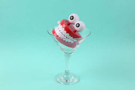 Toy jaw in cocktail glass on blue background. fresh ideas. Minimal party concept, creative layout
