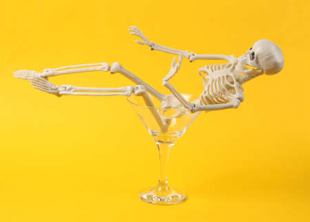 Cocktail glass with skeleton on yellow background. fresh ideas. Minimal party concept, creative layoutの写真素材