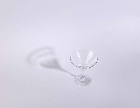 Minimalistic shot of empty cocktail glass with long trending shadow on gray backgroundの写真素材