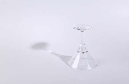 Minimalistic shot of empty cocktail glass with long trending shadow on gray background