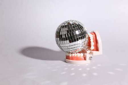 Jaw with disco ball on gray background. Minimal party concept