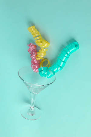 Cocktail glass with serpentine on a blue mint background. Minimal christmas party conceptの写真素材