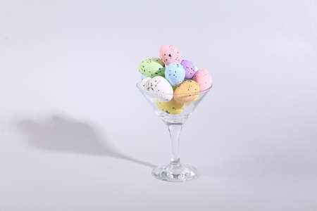 Cocktail glass with colored eggs on gray background. creative ideas. Minimal Easter concept. concept...