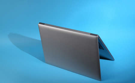 Folded laptop on blue background with long shadows. minimal layoutの写真素材