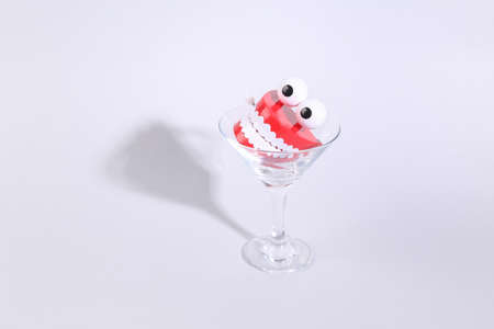 Toy jaw in cocktail glass on gray background. fresh ideas. Minimal party concept, creative layout
