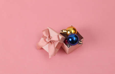 Gift box with christmas toys on pink background