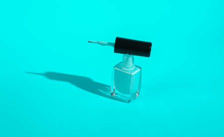 Bottle of turquoise nail polish on turquoise background. Minimal beauty concept