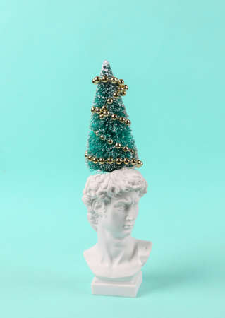 Plaster bust of David with Christmas tree, garland on turquoise background. christmas or new year minimal layoutの写真素材