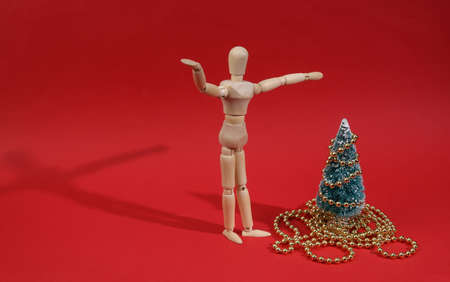 Merry Christmas. Wooden Puppet decorates Christmas tree on red backgroundの写真素材