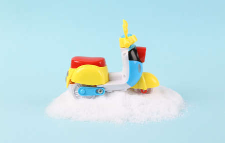 Toy scooter stuck in a snowdrift on a turquoise background