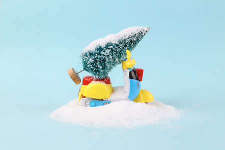 Toy scooter with Christmas tree stuck in snowdrift. blue background. new year, christmas compositionの写真素材