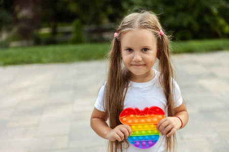Portrait of a cute little girl with antistress pop it toy outdoorsの写真素材