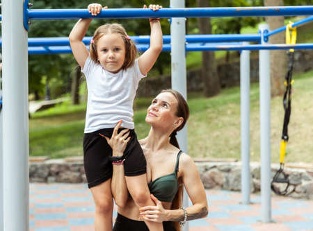 Young athletic mom will walk her daughter to train on the training ground. active family. physical...