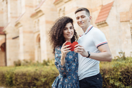 Beautiful young couple holding heart, showing their love against the background of urban architecture. love, romantic conceptの写真素材