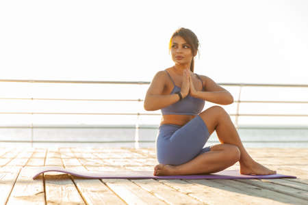 Young beautiful fit woman practicing yoga on the beach