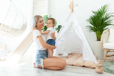 Happy woman mom and her little daughter at home in Children's room with wigwam. Maternal care concept. Spend time together. loving family.の写真素材