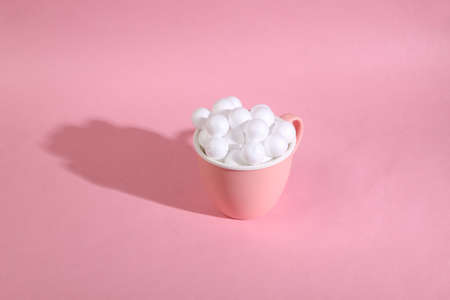 Ceramic cup with white balls on a pink background. Minimalistic still lifeの写真素材