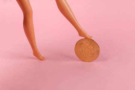 Doll feet roll bitcoin on pink backgroundの写真素材