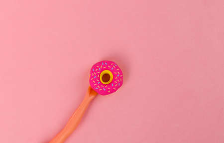 The doll's hand holding donut on pink background. minimal concept. creative layoutの写真素材