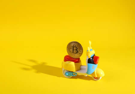 Toy moped with bitcoin on yellow backgroundの写真素材