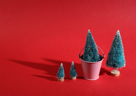 Minimal christmas concept. Christmas trees with a bucket on a bright red backgroundの写真素材