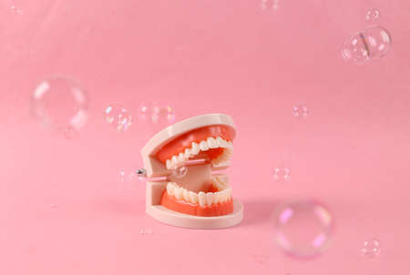 Human jaw model with floating soap bubbles on a pink background. minimal layoutの写真素材