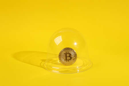 Golden bitcoin under transparent dome on yellow background. protection, isolation concept. minimal layoutの写真素材