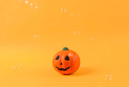 Halloween pumpkin jack with soaring soap bubbles on a yellow background. halloween minimal layout