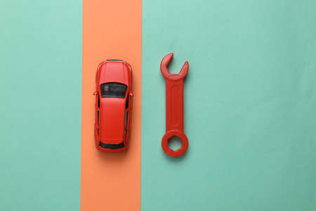 Toy car model wrench on blue pink background. Auto service, repair concept. top view