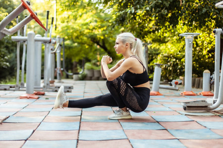Young fit woman squats on one leg on sports ground