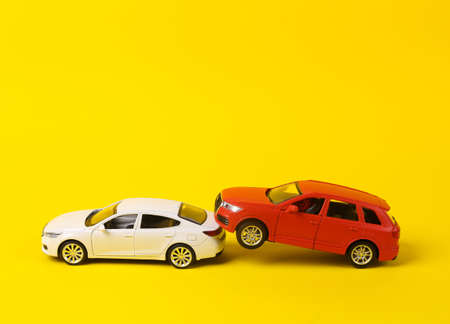 Two mini toy car crash on a yellow background, incident, car traffic accidentの写真素材