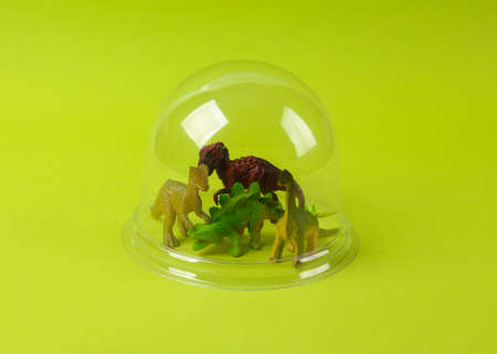 Toy dinosaurus under transparent dome on green background