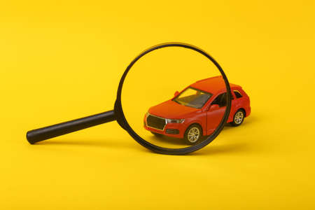 Toy car model through magnifying glass on yellow backgroundの写真素材