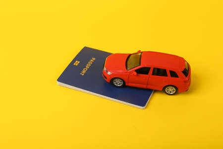 Toy car model with a passport on a yellow background. travel conceptの写真素材