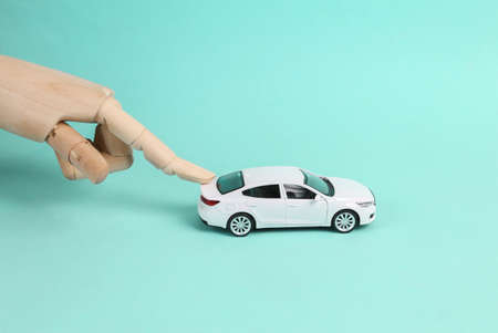 Hand pushing toy car model on blue background
