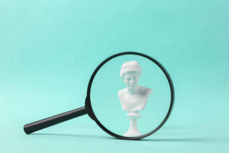 Antique statue of venus through a magnifying glass on a blue backgroundの写真素材