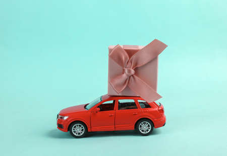 Toy car model with a gift box on blue background. Delivery, holiday conceptの写真素材