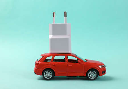 Toy model of an auto with a charger on blue background. electric carの写真素材