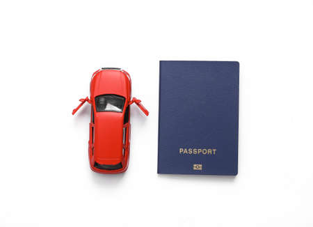 Toy car model with a passport on white background. travel concept. top view
