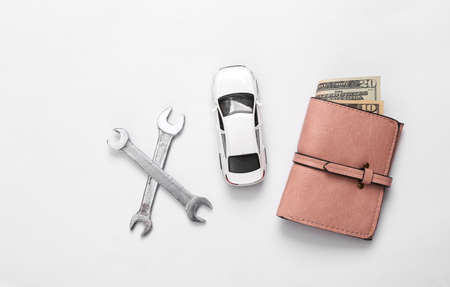 Toy car model with wrench and purse on white background. Auto service, repair concept. top view