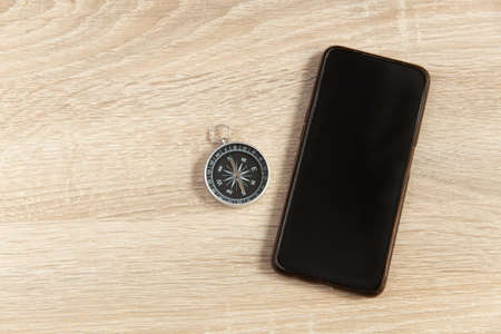 Smartphone with compass on wooden table. top view