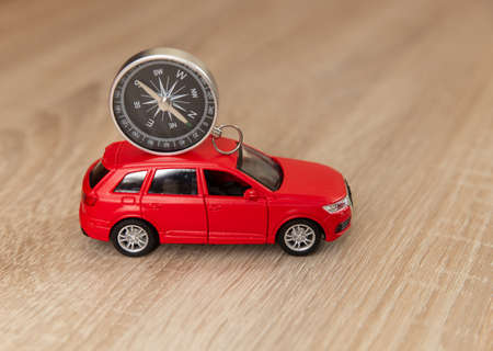 Compass with toy car model on wooden table. travel concept