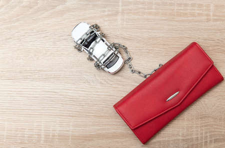 Toy car wrapped in a steel chain with purse on a wooden tableの写真素材