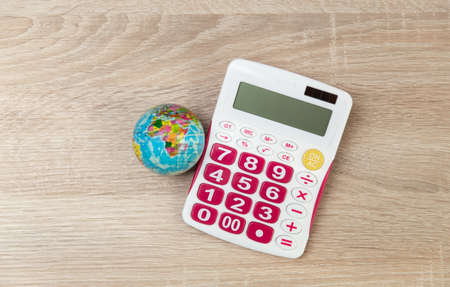 Globe with calculator on wooden table. world economy. top viewの写真素材