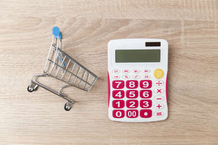 Shopping trolley with calculator on wooden tableの写真素材