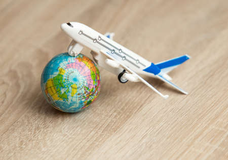 Toy model of a passenger plane with globe on wooden table